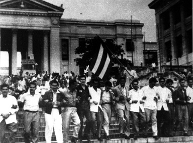 Foto de Inicio del entierro de la Constitución del 40, en la manifestación Raúl Castro sostiene y porta la bandera cubana y en la línea delantera Armando Hart de negro, lleva en sus manos el ejemplar de la Constitución que fue enterrado en la Fragua Martiana. Rec